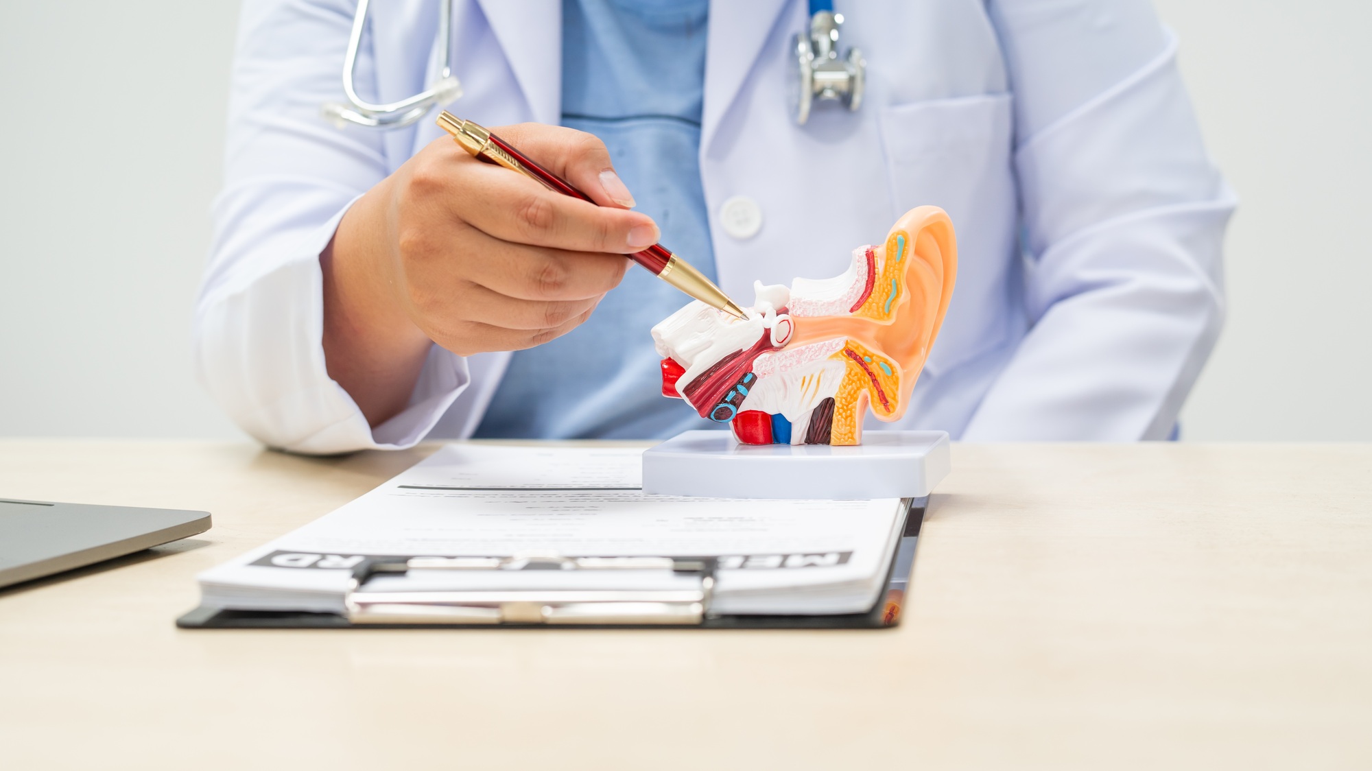 A female doctor sits at a table in a hospital, discussing hearing loss, tinnitus,balance problems