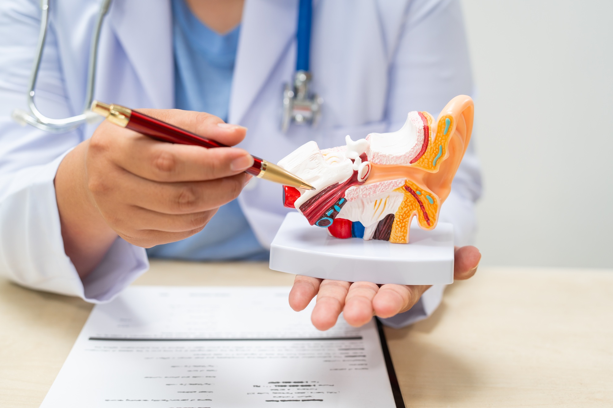 A female doctor sits at a table in a hospital, discussing hearing loss, tinnitus,balance problems