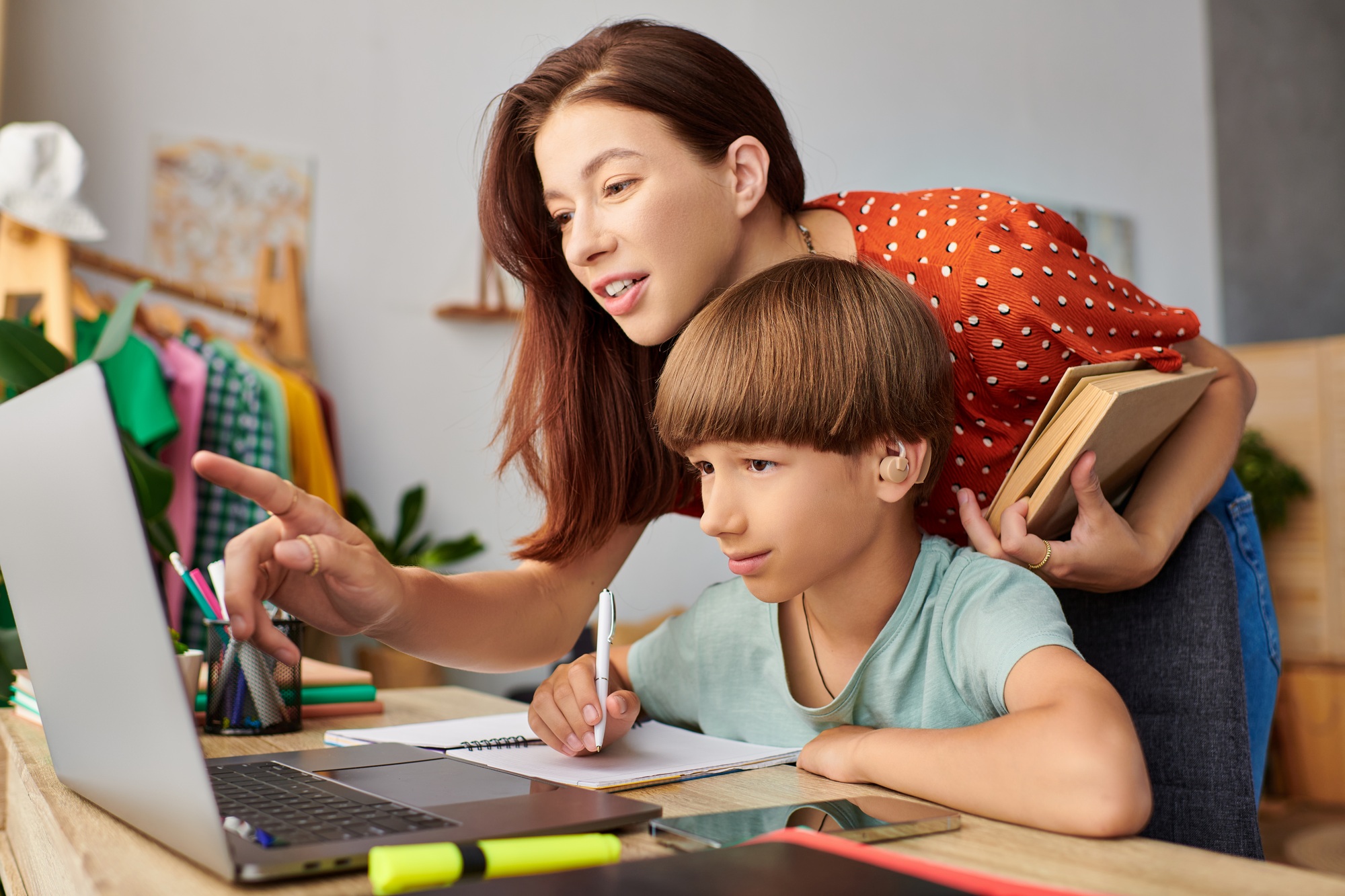 A nurturing mother helps her hearing-impaired son with schoolwork at home during the afternoon