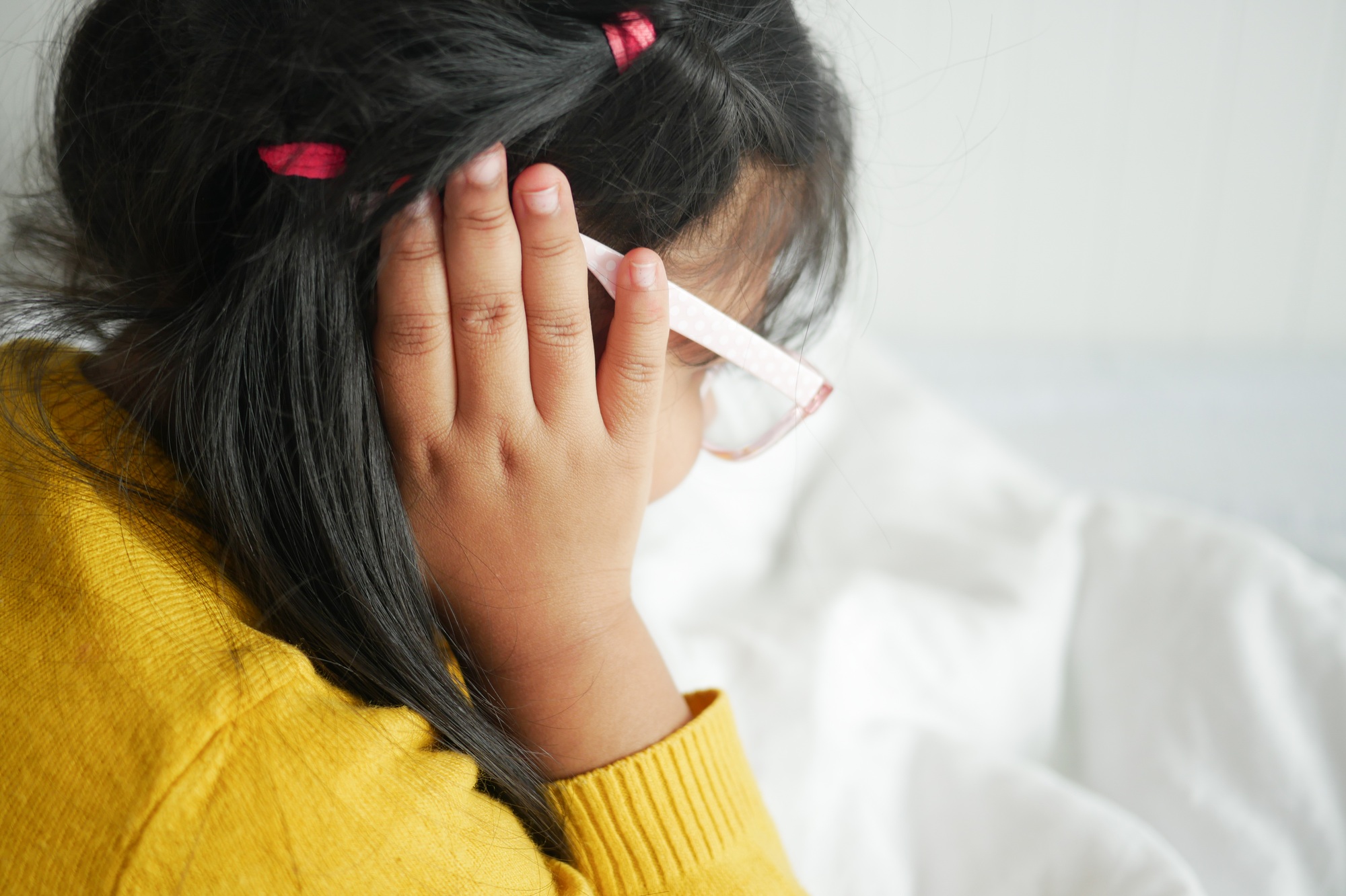 child having ear pain touching his painful ear ,