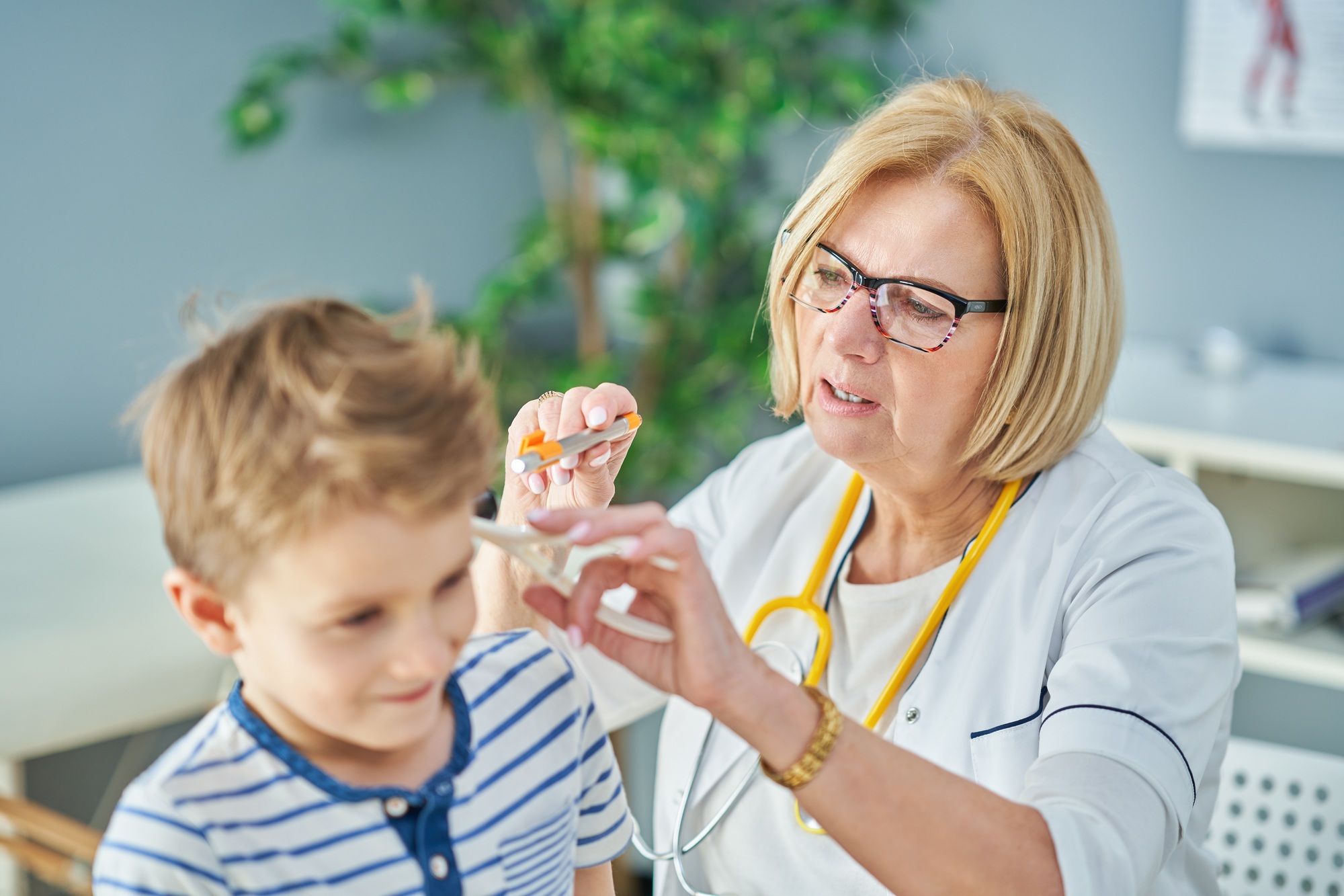 Pediatrician doctor examining little kids in clinic ears check