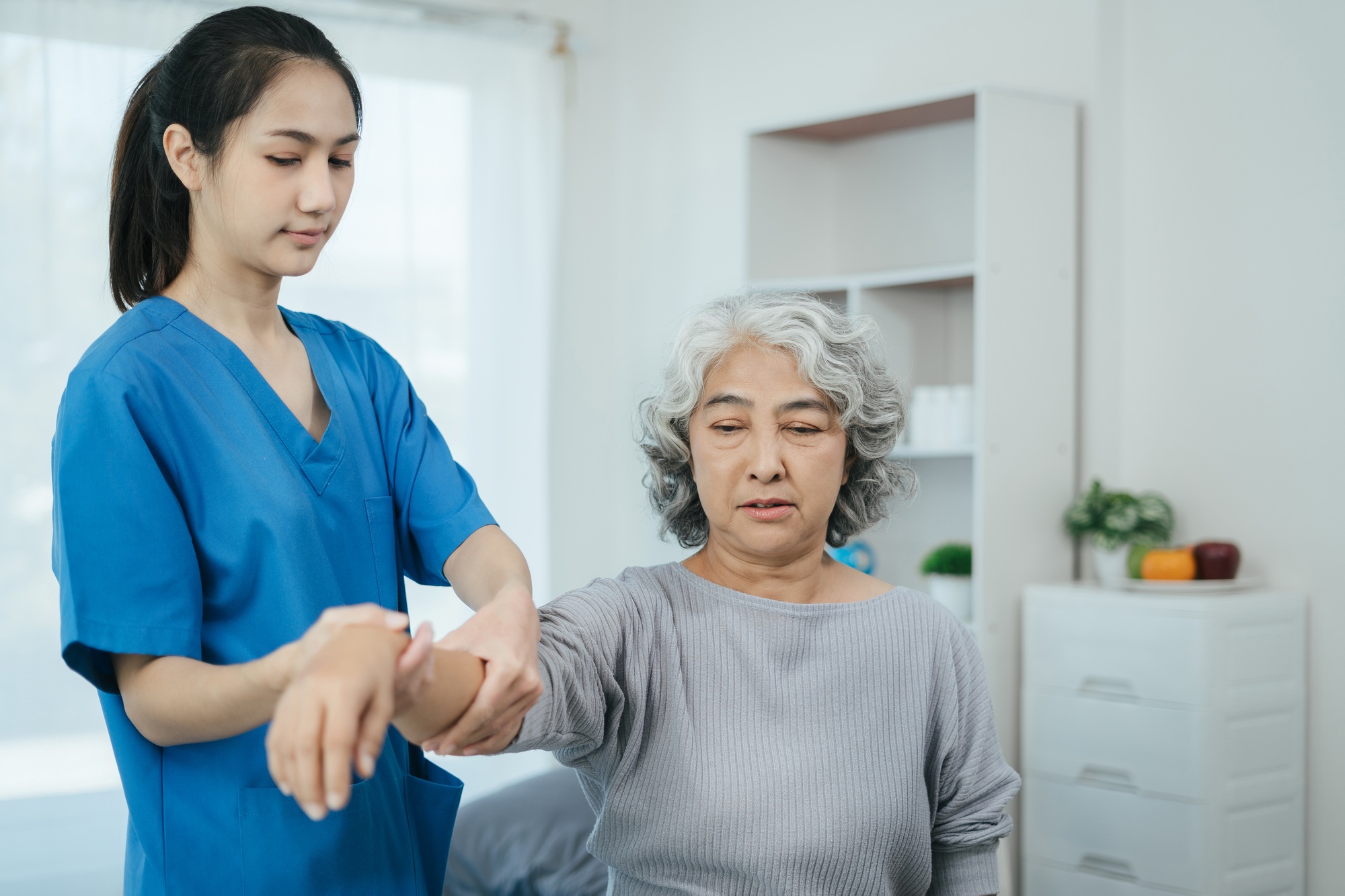 senior woman doing exercise at clinic with physiotherapist.