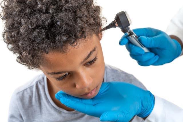 A doctor examines a child's ear with an otoscope during a medical check-up