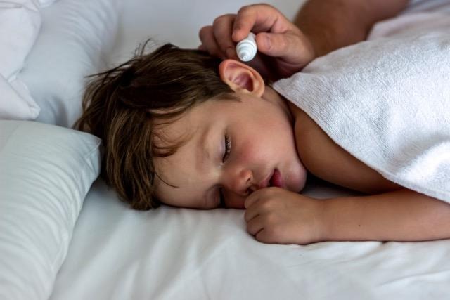 A child peacefully sleeping in bed wrapped in a white towel with soft bedding surrounding them