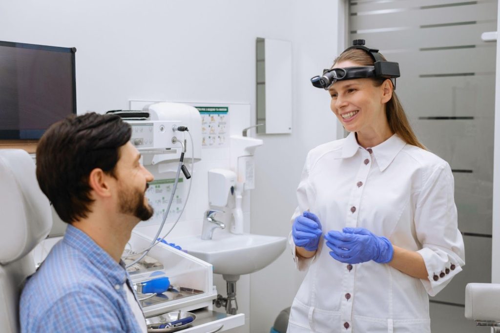 A man and woman seated in a dental office engaged in conversation about dental health