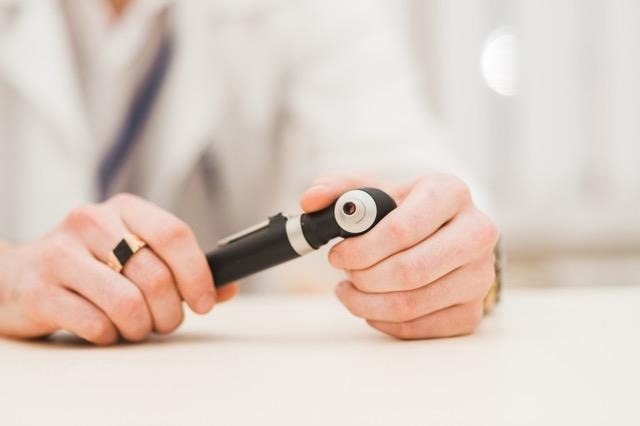 A doctor holds a pen in his hand ready to write notes or prescriptions