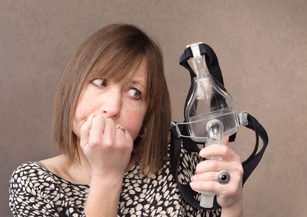 A woman holds a mask over her mouth emphasizing the importance of health and safety measures