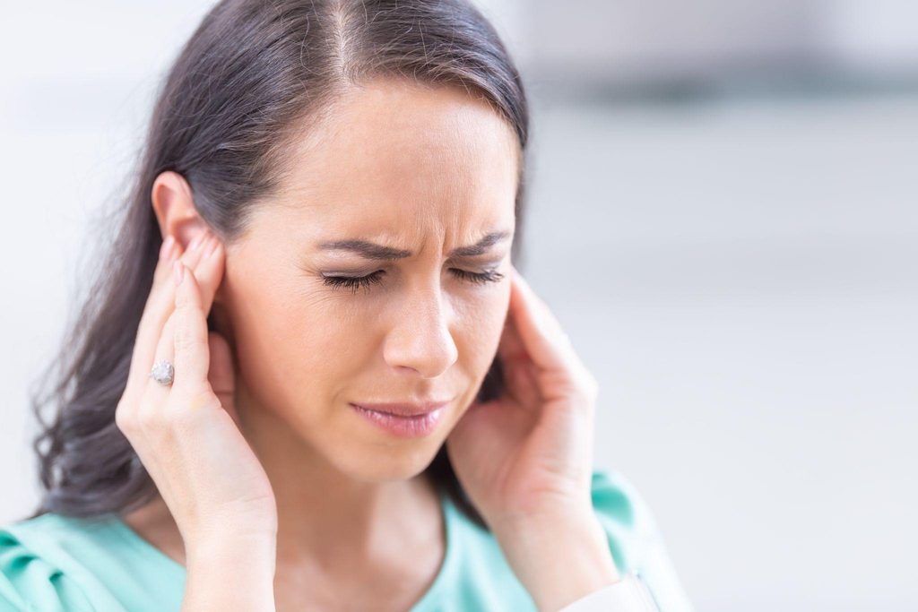 A woman appears distressed pressing her hand against her ear due to pain