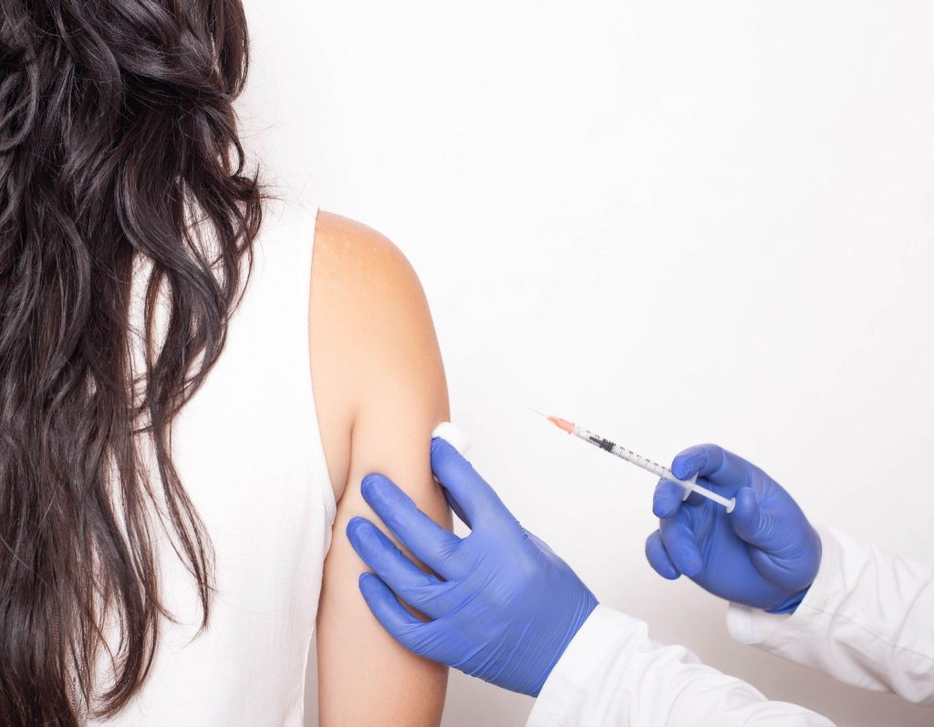 A healthcare professional administers an injection to a woman emphasizing vaccination importance